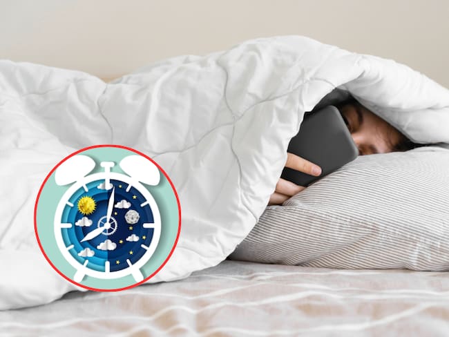 Mujer intentando dormir, mientras ve el celular en la cama arropada (Getty images)
