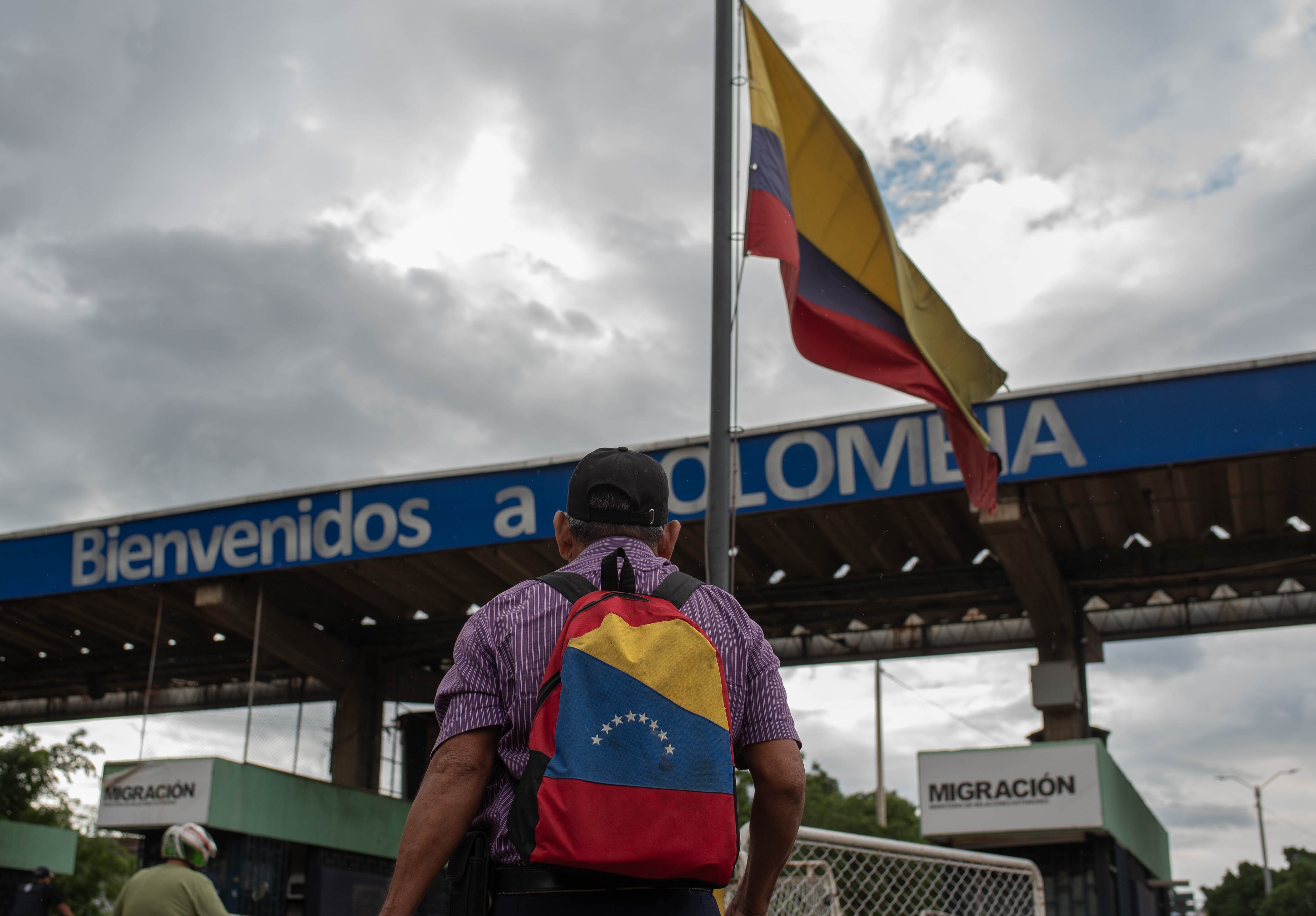Hombre con maleta que tiene bandera venezolana cruza la frontera para ingrsar a Colombia.
(Foto:   Hector Quintanar/Getty Images)