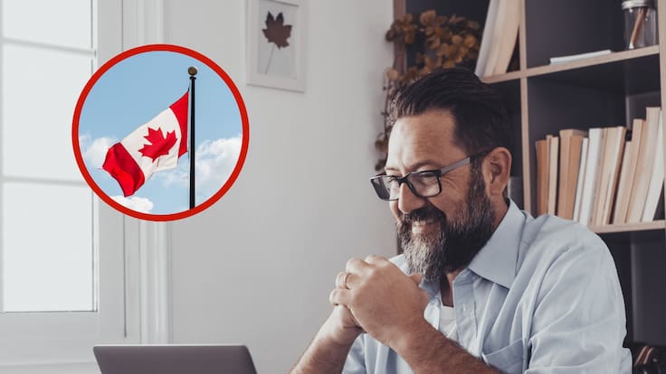 Hombre sentado frente a una computadora y la bandera de Canadá (Fotos vía Getty Images)
