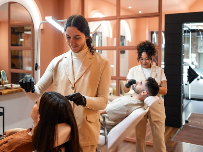 Salón de belleza en donde una mujer y un hombre reciben cortes de pelo (Crédito: Getty Images)
