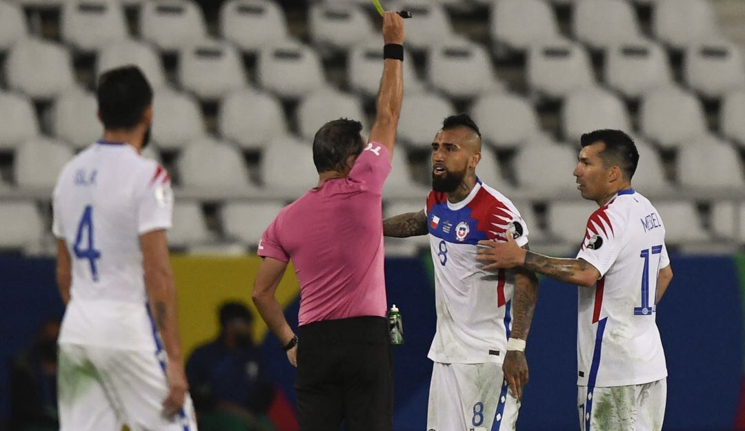 El árbitro Loustau amonesta a Arturo Vidal por protestar durante el juego.