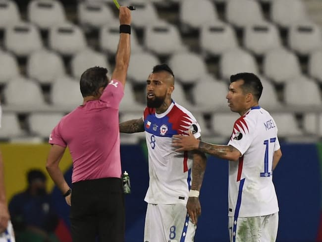 El árbitro Loustau amonesta a Arturo Vidal por protestar durante el juego.