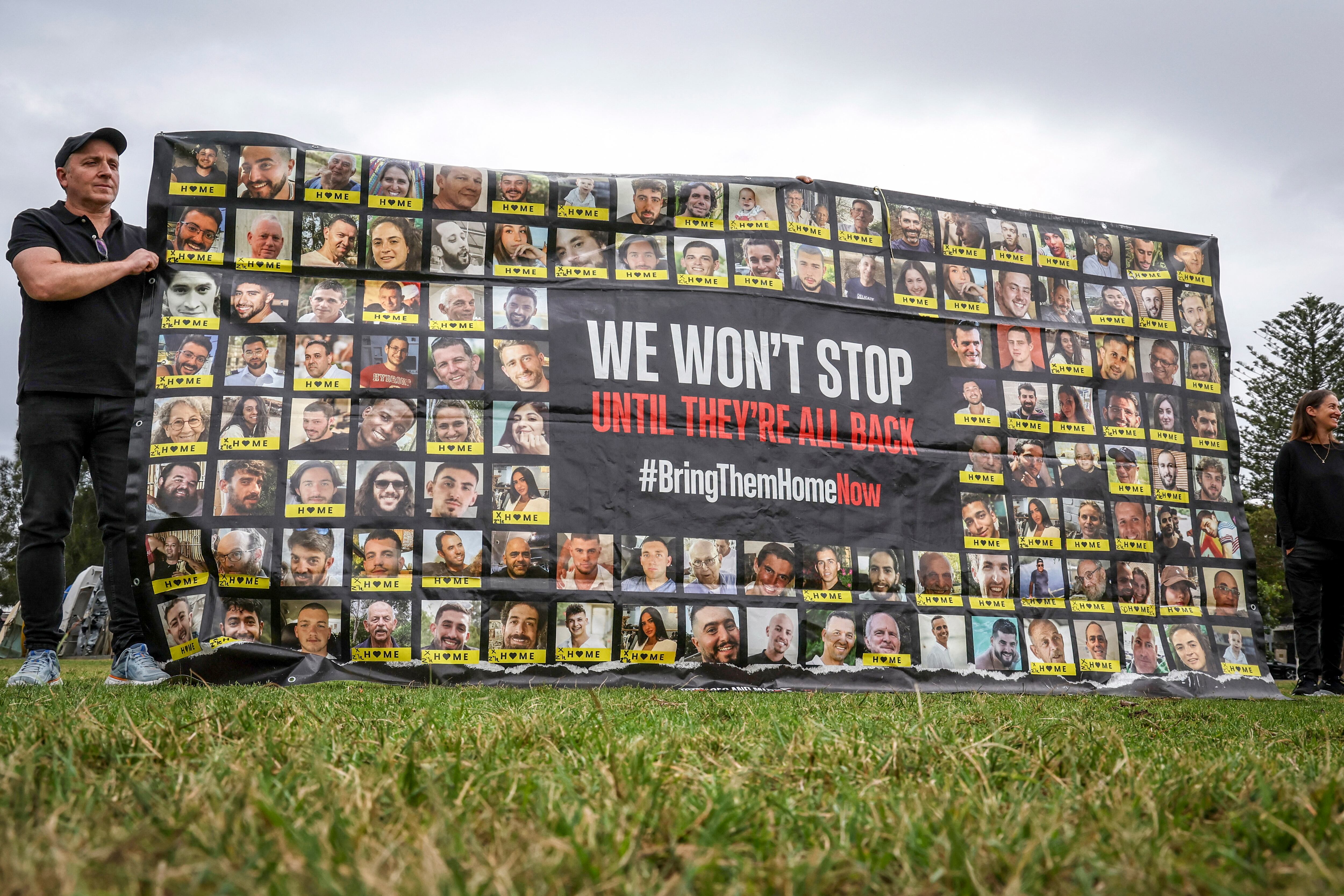 Members of the Australian Jewish community hold a banner bearing the portraits of Israelis held hostage in the Gaza Strip by Palestinian militants during a rally in Sydney on October 7, 2025, to mark the two-year anniversary of the attack by Hamas on Israel, which sparked the war in Gaza. Hamas's October 2023 attack resulted in the deaths of 1,219 people on Israeli side, mostly civilians, according to an AFP tally based on official Israeli figures. Militants also abducted 251 hostages into Gaza, of whom 47 remain captive, including 25 the Israeli military says are dead. (Photo by DAVID GRAY / AFP)