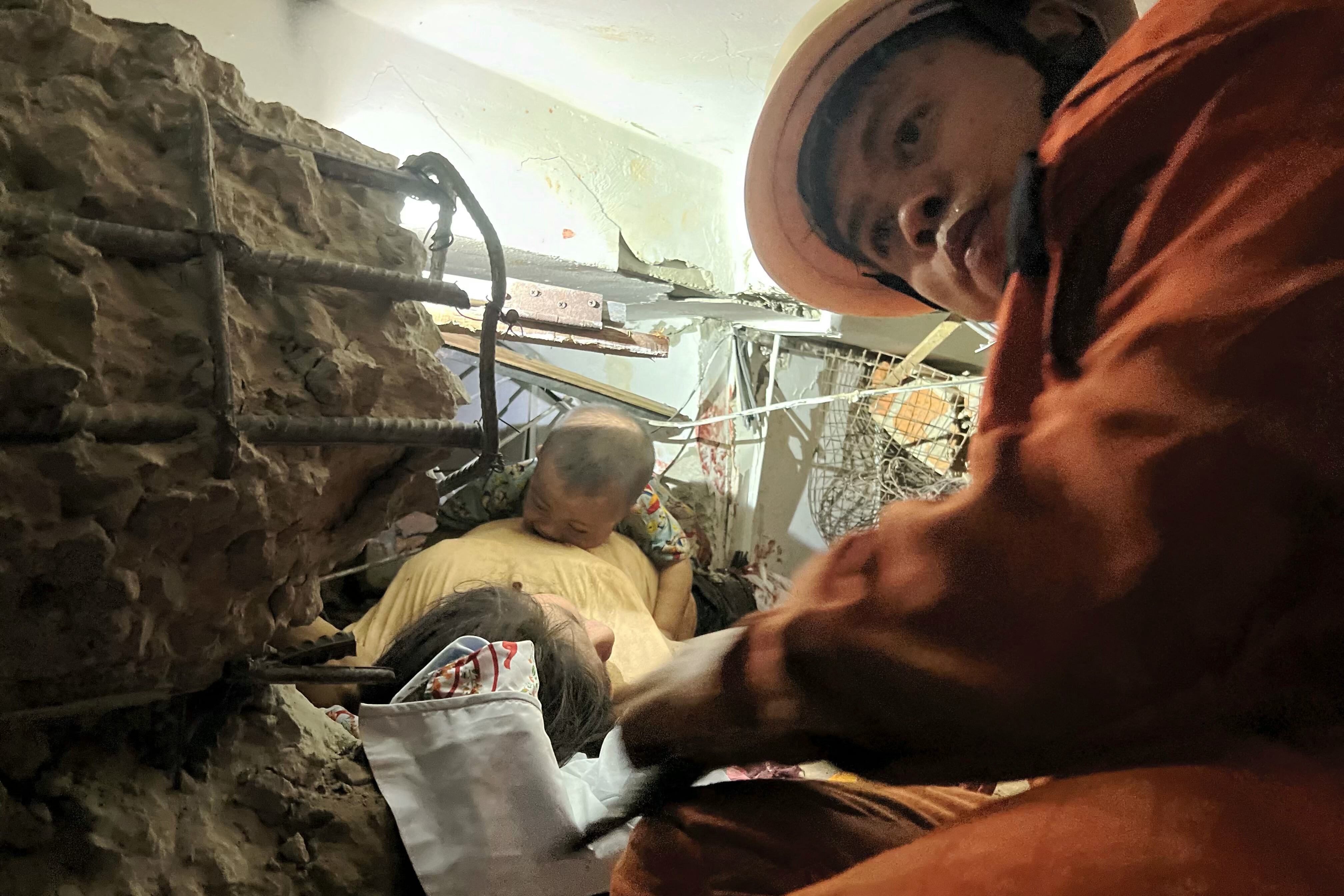 Un rescatista trabaja para liberar a una mujer y su bebé de un edificio colapsado en Birmania.
(Foto: SAI AUNG MAIN/AFP via Getty Images)