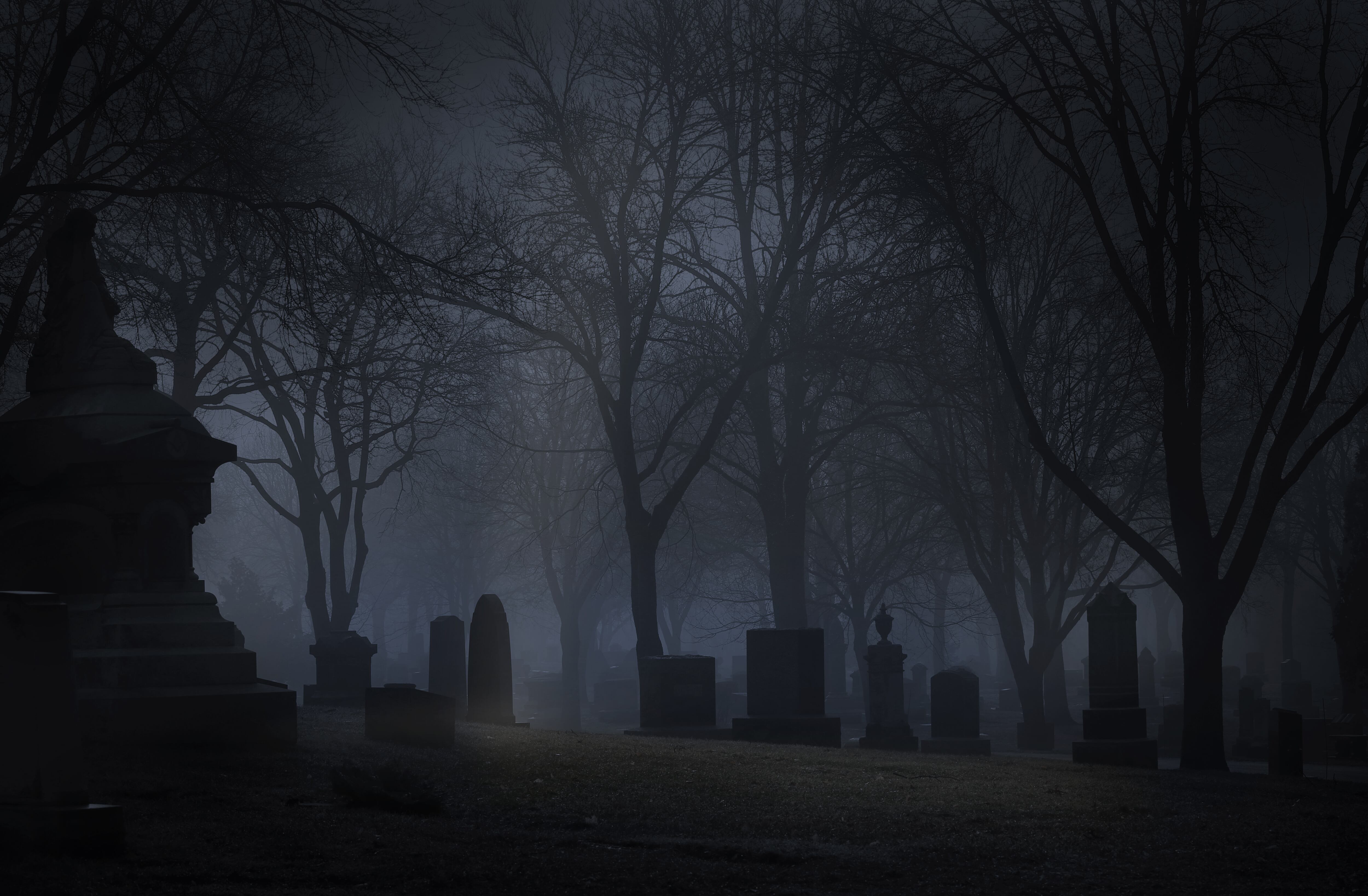 Spooky cemetery at night with fog. Desaturated color.