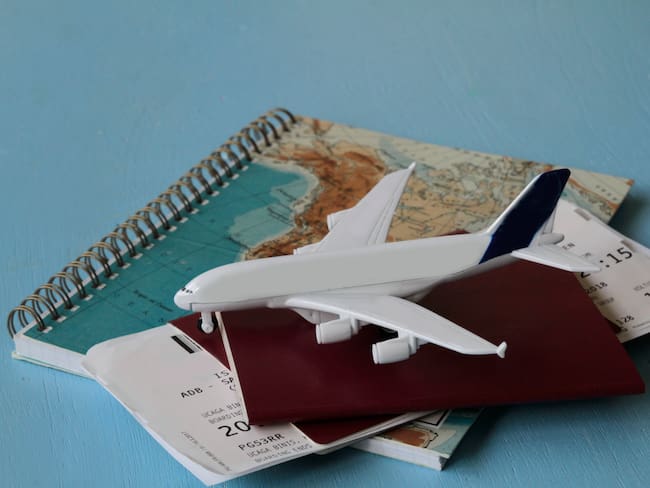En la imagen se ve un pasaporte, tarjetas de embarque, un mapa y un avión / Foto: GettyImages