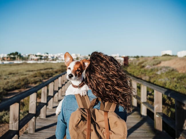 Mujer con perro en brazos cruzando un puente (Getty Images)