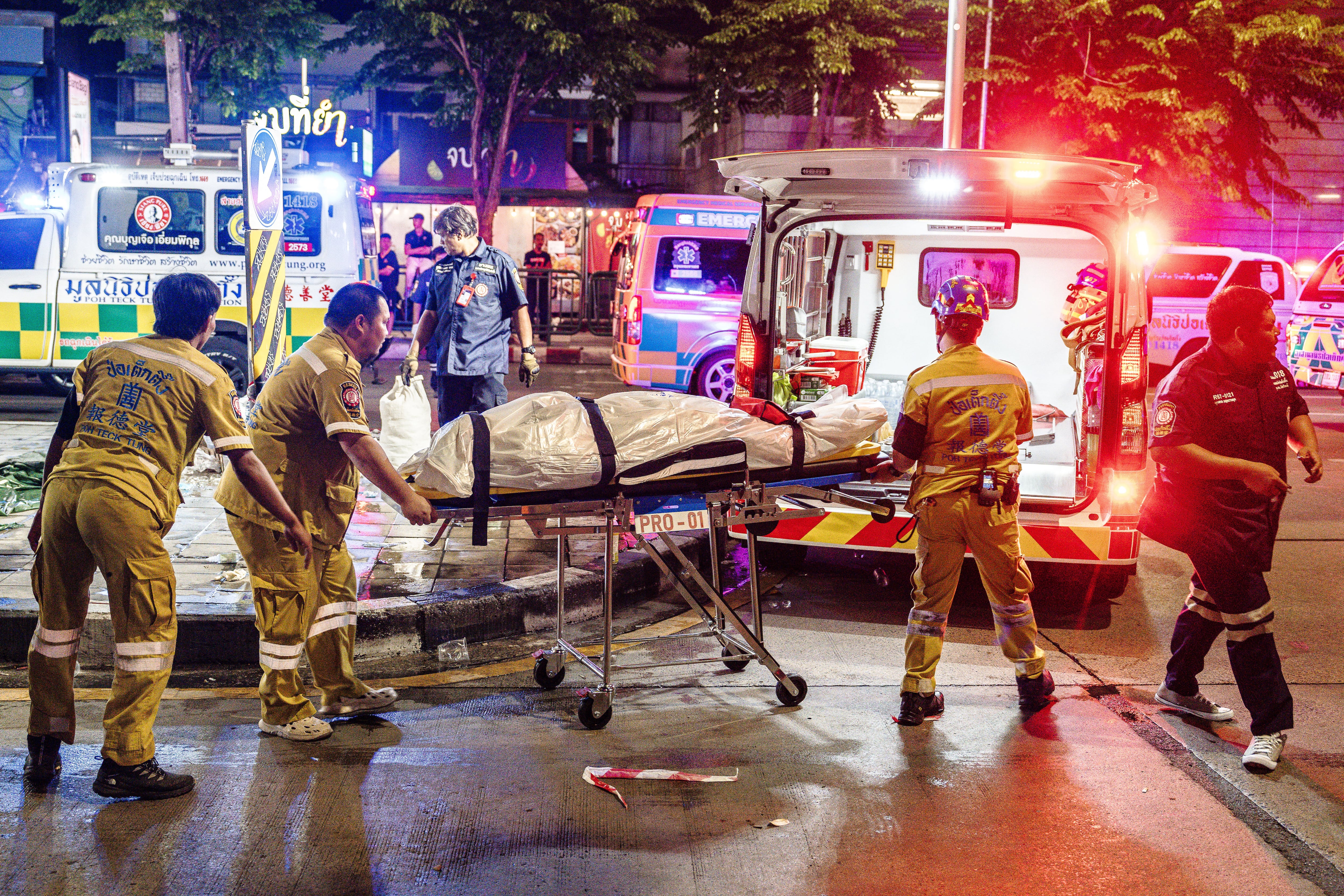 Emergency workers prepare to place the body of a victim into an ambulance after a fire at the Rong Beer Na Lat Phrao bar in Bangkok on July 13, 2026. A massive fire in a Bangkok bar late on July 12 killed at least 27 people and injured dozens, sending screaming patrons fleeing as flames shot from the entrance, according to officials and video verified by AFP. (Photo by chanakarn LAOSARAKHAM / AFP)