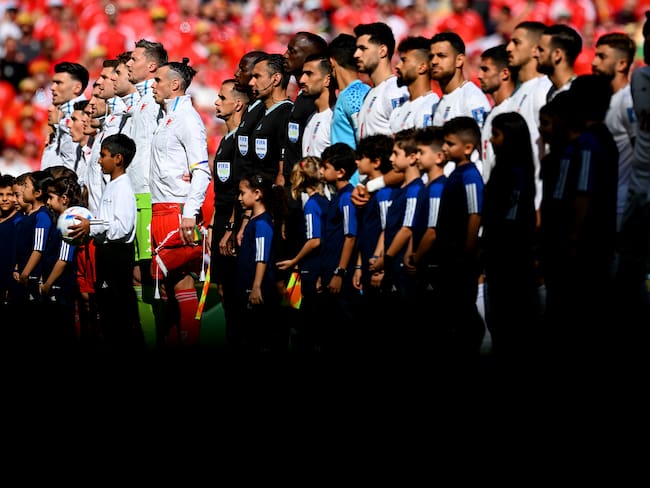 DOHA, QATAR - NOVEMBER 25: Players and match officials line up prior to the FIFA World Cup Qatar 2022 Group B match between Wales and IR Iran at Ahmad Bin Ali Stadium on November 25, 2022 in Doha, Qatar. (Photo by Matthias Hangst/Getty Images)