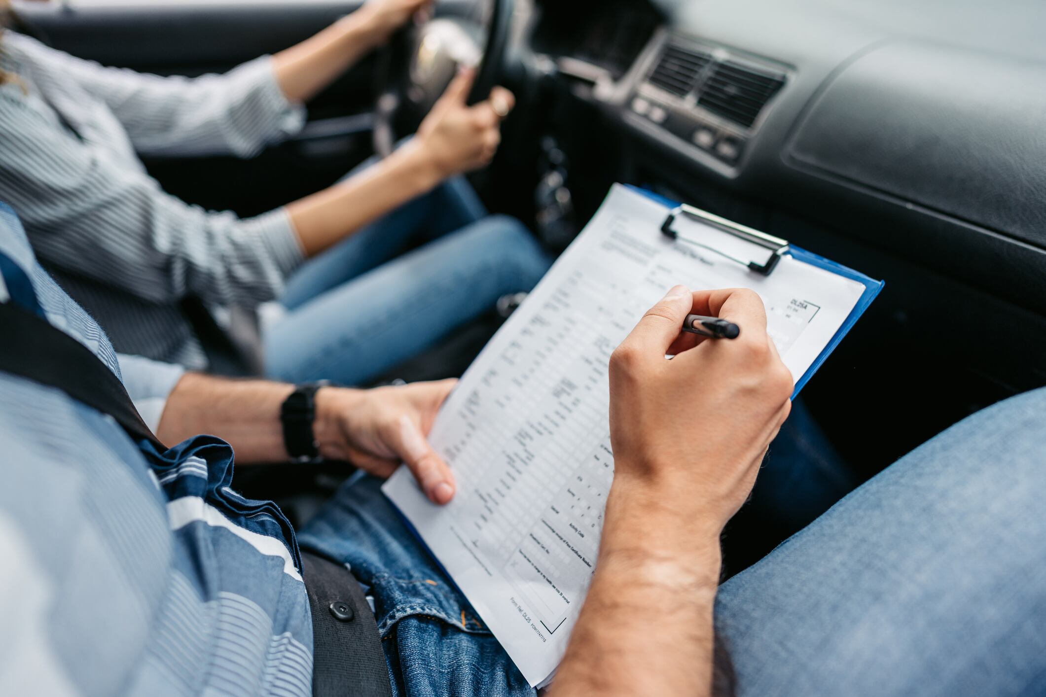 Instructor de manejo calificando a una alumna usando una lista de verificación (Foto vía Getty Images)