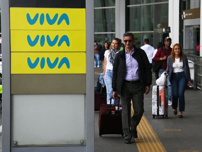 People pass by an advertising board of Viva Air outside the El Dorado international airport in Bogota on February 28, 2023. - The Colombian low-cost airline Viva Air suspended its operations last Monday due to financial problems, according to a company statement. (Photo by Juan Barreto / AFP) (Photo by JUAN BARRETO/AFP via Getty Images)