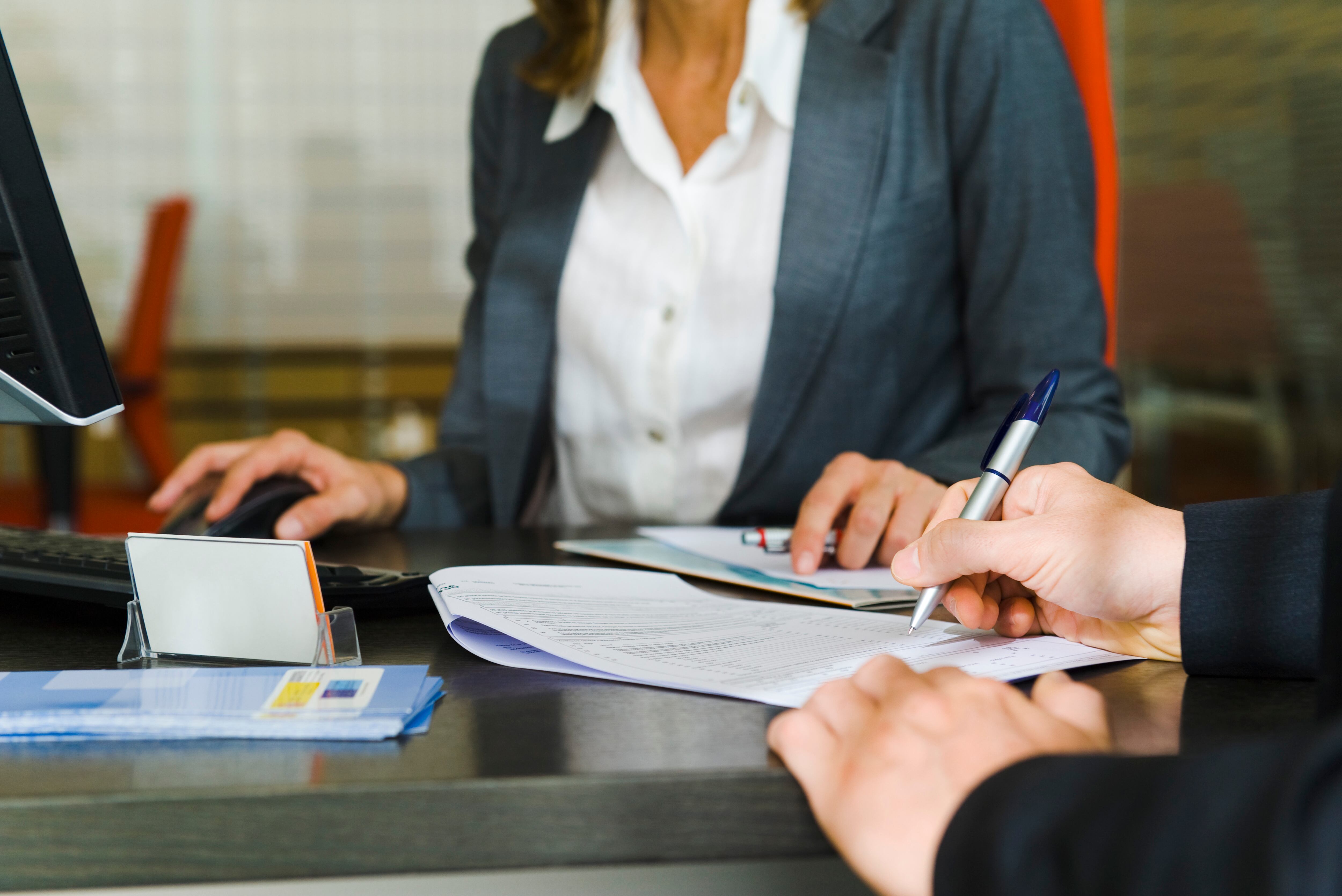Hombre firmando y funcionaria de banco (Getty Images)