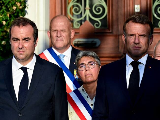 France's Minister of Armed Forces Sebastien Lecornu (L) and France's President Emmanuel Macron stand at attention during a ceremony marking the 81st anniversary of the liberation of Bormes-les-Mimosas during World War II, southeastern France, on August 17, 2025. (Photo by Miguel MEDINA / POOL / AFP)