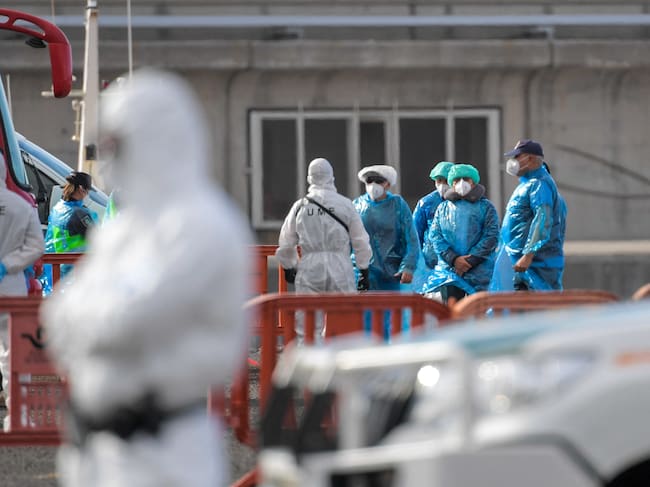 Passengers wearing a blue protective suits board a military bus after being evacuated from the Dutch flagged hantavirus-stricken cruise ship MV Hondius at the industrial port of Granadilla de Abona on the island of Tenerife in Spain's Canary Islands on May 10, 2026. Repatriation flights for the nearly 150 passengers onboard the ship hit by a deadly hantavirus outbreak began as passengers were transferred to shore on smaller vessels then by bus to the airport to be flown home after weeks at sea. (Photo by JORGE GUERRERO / AFP)