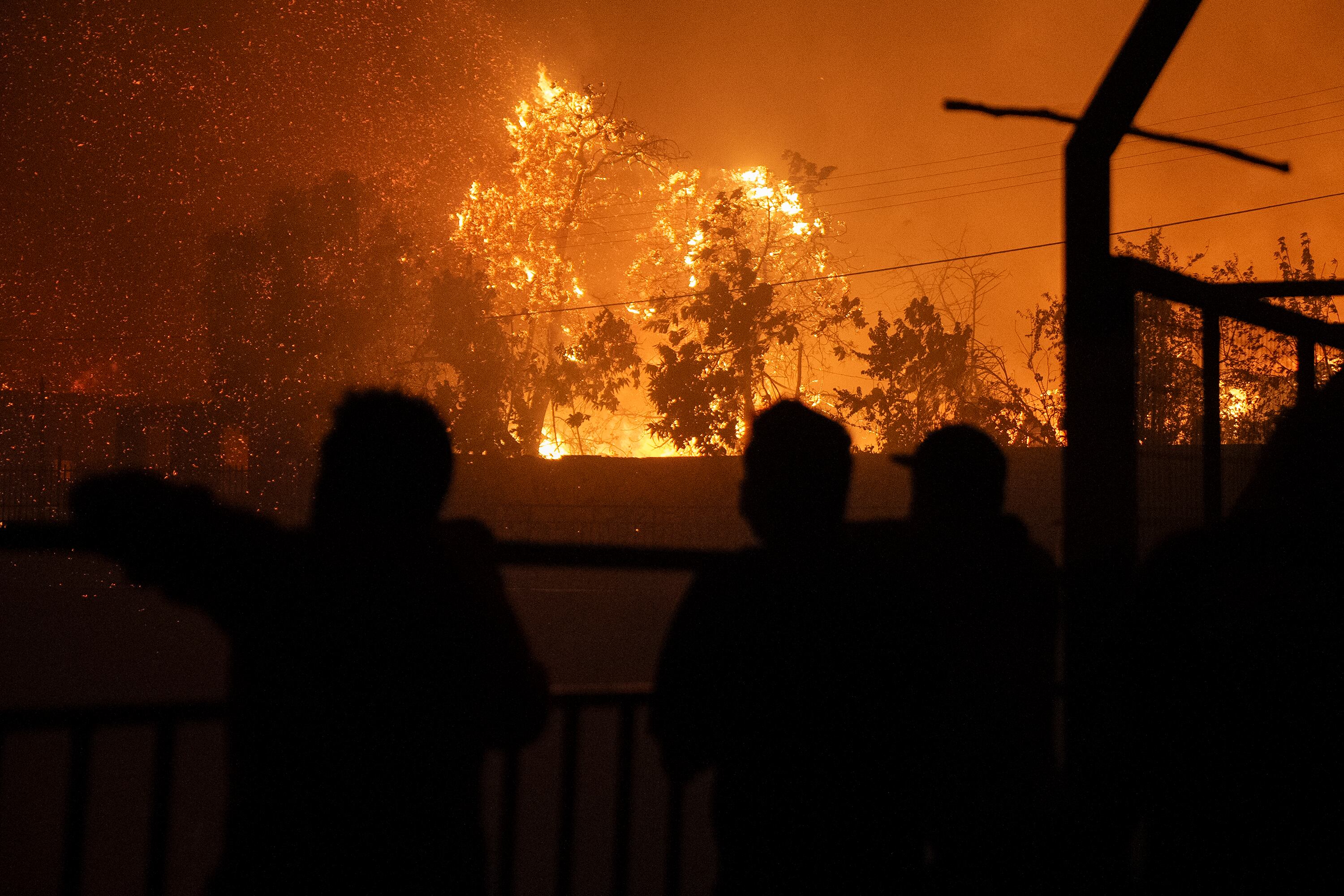 VIÑA DEL MAR (CHILE), 02/02/2024.- Personas observan un incendio que comenzó en la reserva natural del lago Peñuelas y ha llegado hasta las zonas urbanas hoy, en Viña del Mar (Chile). El primer gran incendio forestal de la temporada estival en los alrededores de la ciudades costeras de Valparaíso y Viña del Mar obligó este viernes a evacuar varias comunas del interior, amenaza aún con llegar a ambas localidades y ha cubierto de denso humo negro toda la costa, llegando incluso a playas más lejanas como Concón, Quintero y Maitencillo, situadas a casi un centenar de kilómetros del epicentro de la catástrofe. EFE/ Adriana Thomasa