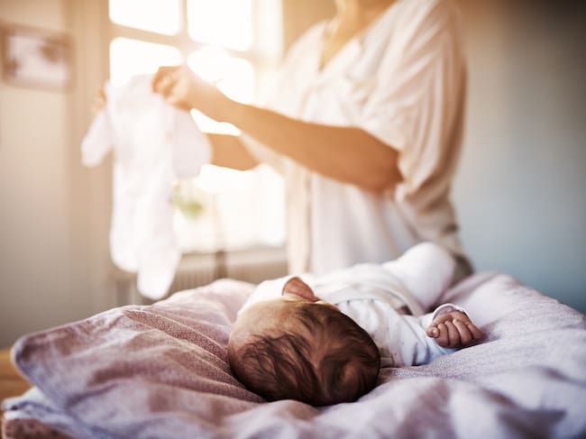 Shot of a mother changing her newborn baby girl at home