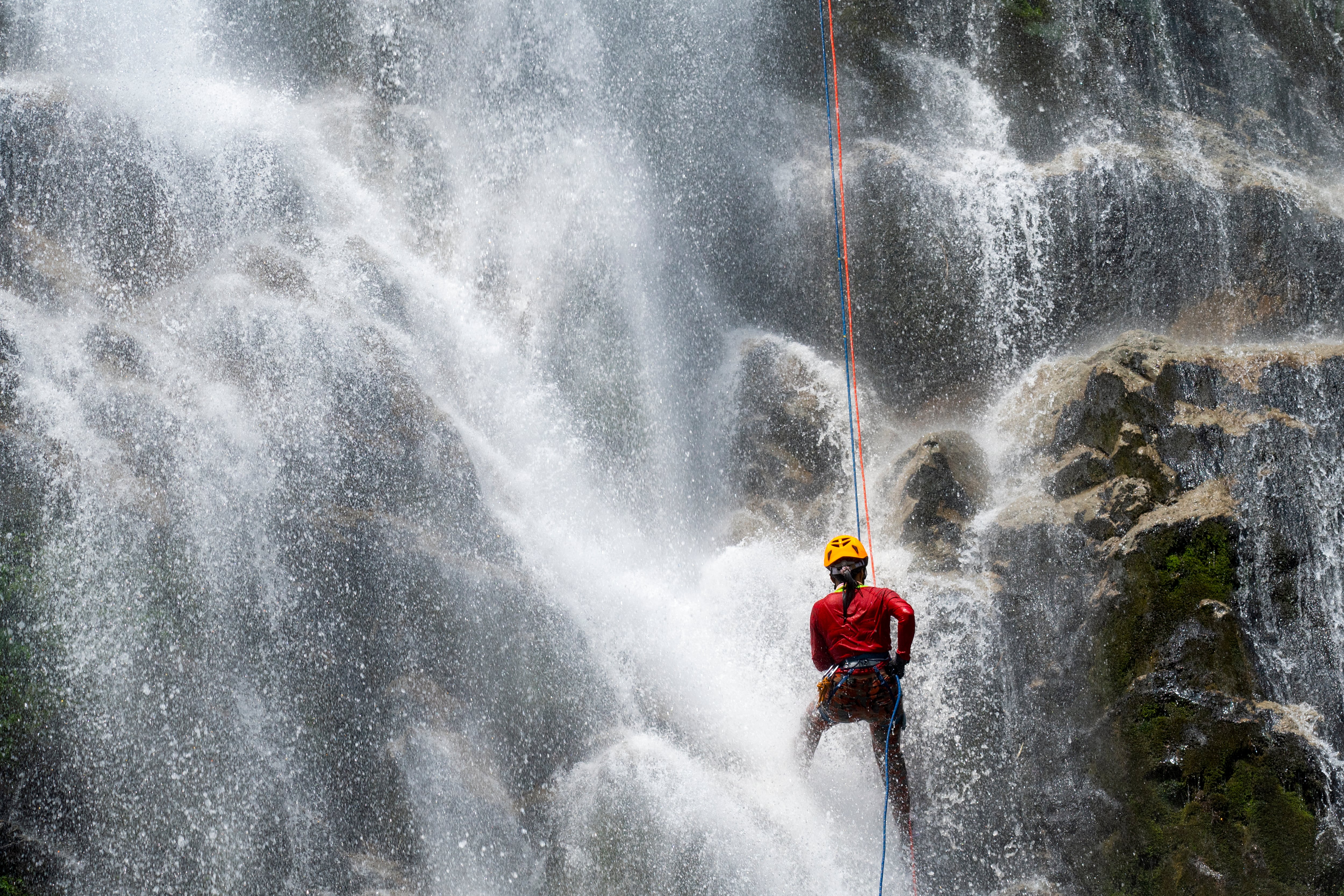 Mujer practicando torrentismo en una cascada - Foto vía Getty Images