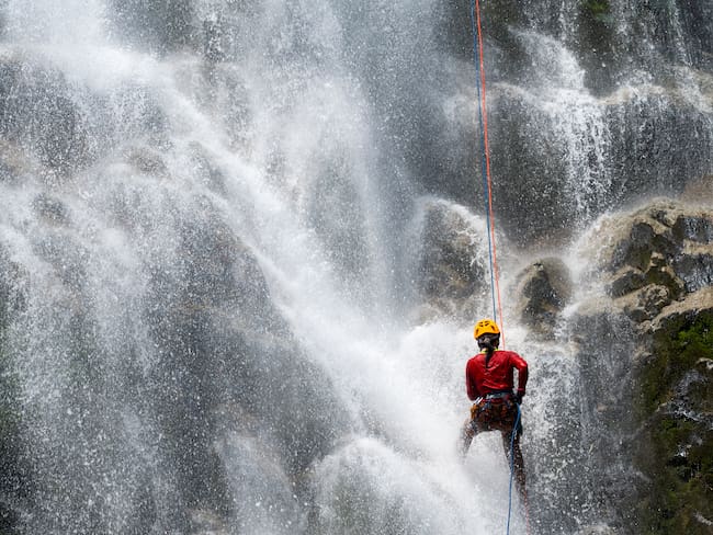 Mujer practicando torrentismo en una cascada - Foto vía Getty Images