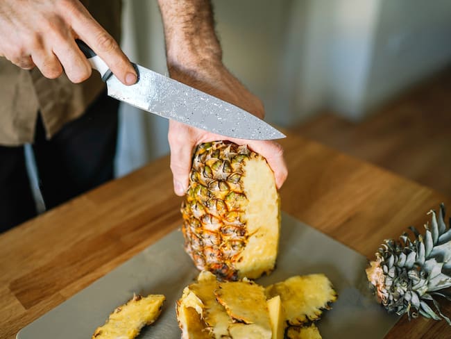 Persona cortando piña para su consumo, imagen de referencia // Getty Images