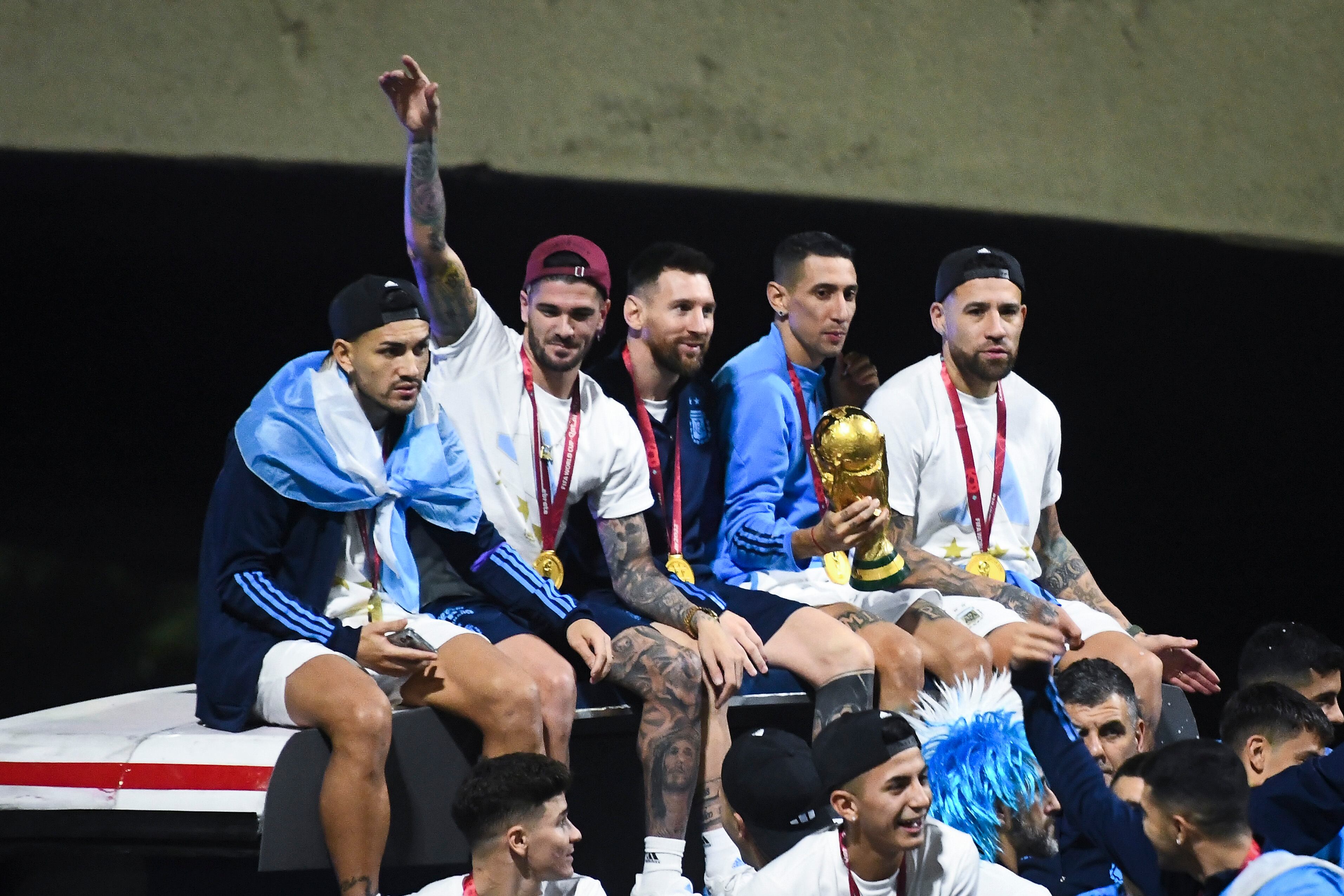 BUENOS AIRES, ARGENTINA - DECEMBER 20:  (L-R) Leandro Paredes, Rodrigo De Paul, Lionel Messi, Angel Di Maria and Nicolas Otamendi celebrate on the bus during the arrival of the Argentina men's national football team after winning the FIFA World Cup Qatar 2022 on December 20, 2022 in Buenos Aires, Argentina. (Photo by Rodrigo Valle/Getty Images)