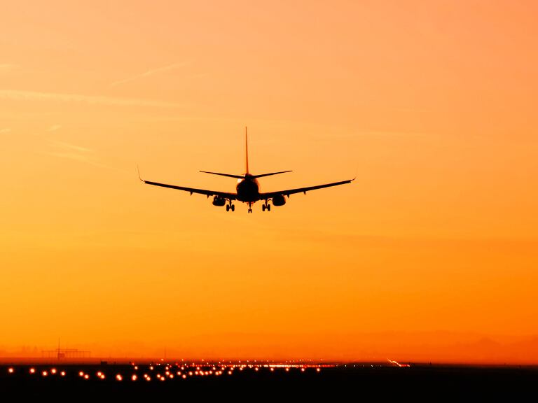 El avión llegando al aeropuerto con un atardecer de color naranja (Getty Images)