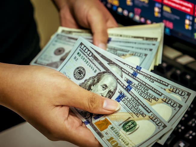 Mujer contando varios dólares estadounidenses (Getty Images)