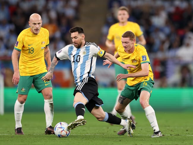 DOHA, QATAR - DECEMBER 03: Lionel Messi of Argentina controls the ball against Kye Rowles and Aaron Mooy of Australia during the FIFA World Cup Qatar 2022 Round of 16 match between Argentina and Australia at Ahmad Bin Ali Stadium on December 03, 2022 in Doha, Qatar. (Photo by Michael Steele/Getty Images)
