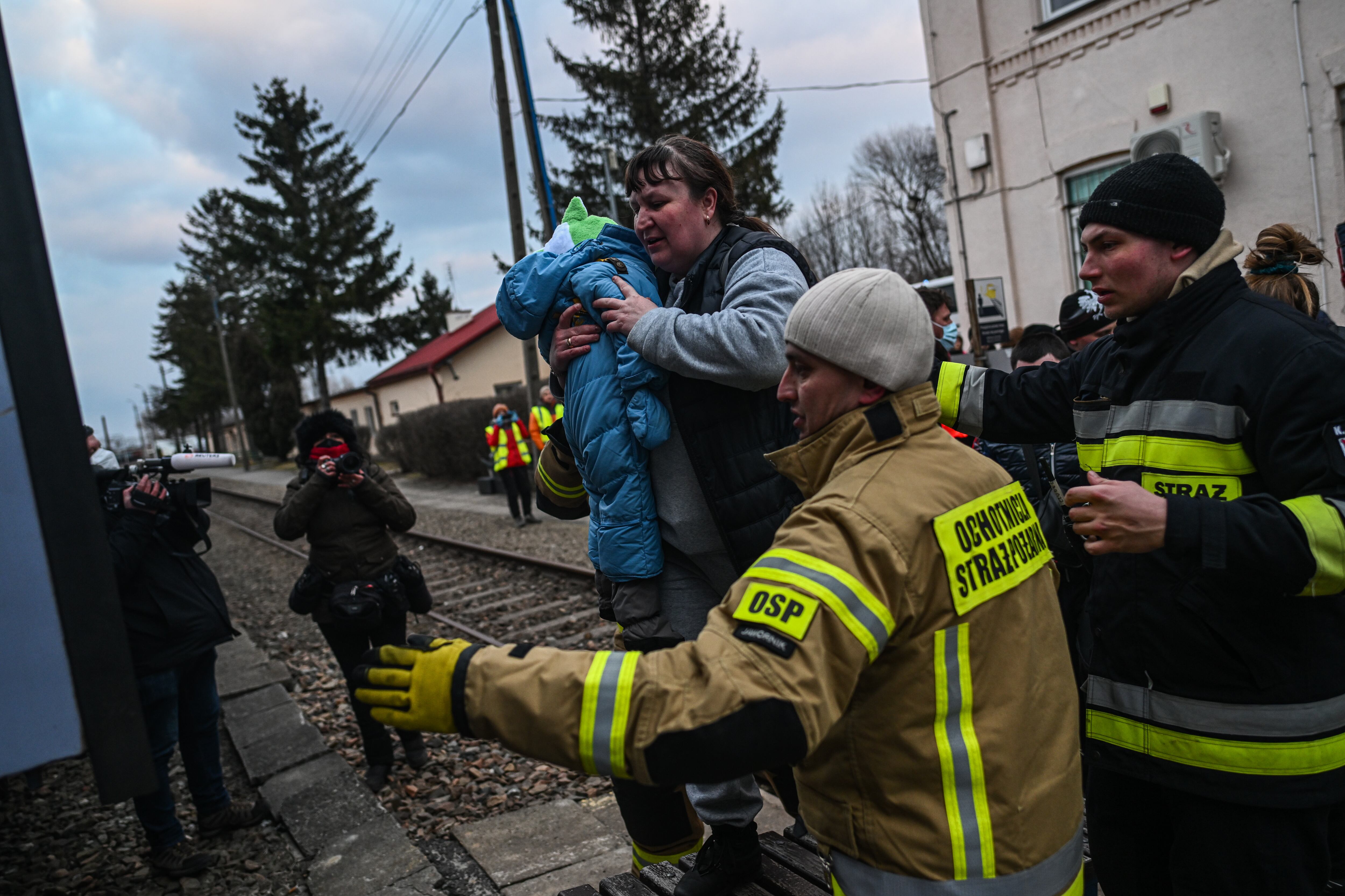 MEDYKA, POLAND - MARCH 10:A woman carries a children as they exit a busin order to be transported into train wagon transformed for medical transport on March 10, 2022 in Medyka, Poland. Around 20 children  with chronic illnesses and cancer diagnosis together with 50 family members who were being treated in a Harkiv hospital were transported by bus to Medyka border town in Poland today. On their arrival they have been loaded to a Polish medical train and will be taken to Gdynia hospital. Over two million people have fled Ukraine since Russia launched a large-scale attack on the country on February 24. (Photo by Omar Marques/Getty Images)