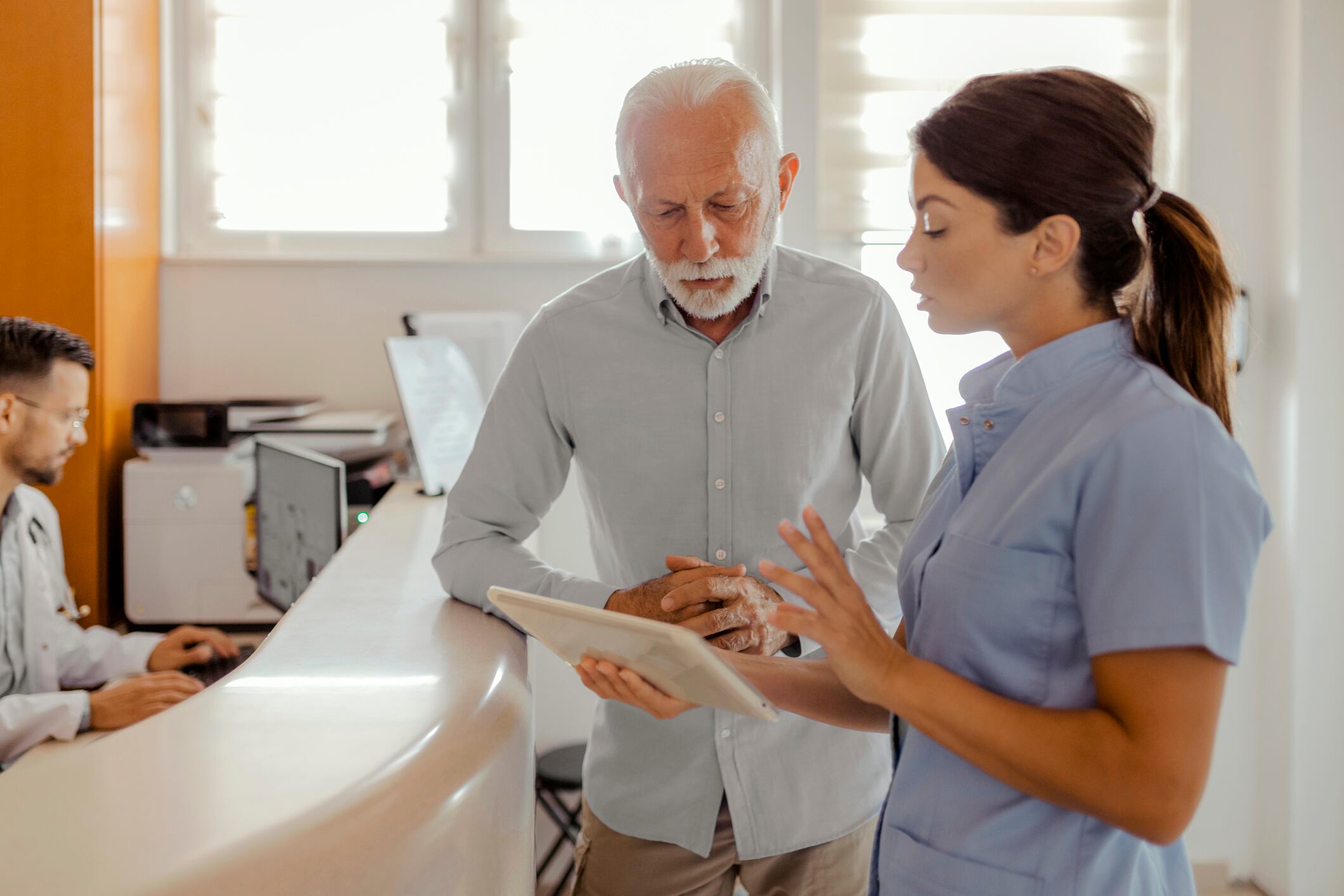 Médico con tableta hablando con un paciente mayor en el hospital (Getty Images)
