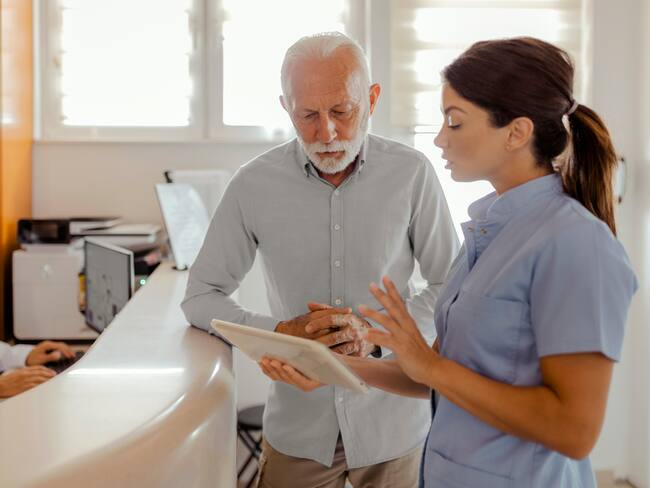 Médico con tableta hablando con un paciente mayor en el hospital (Getty Images)