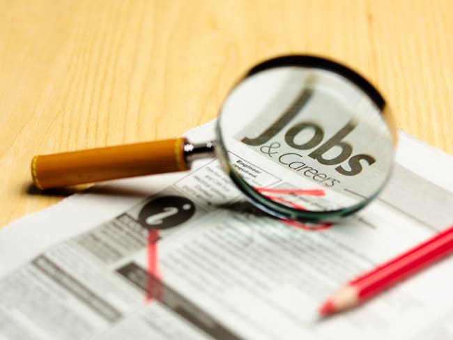 Lupa sobre la palabra trabajo, falsas ofertas de empleo - Foto vía Getty Images