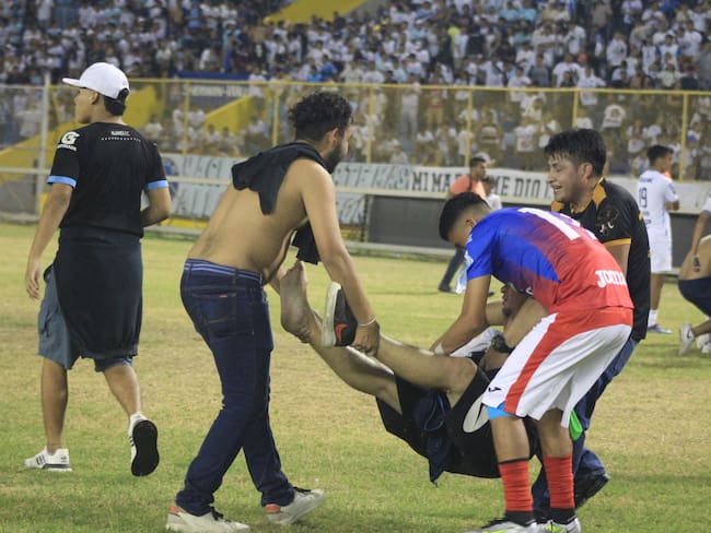 Futbolistas y asistentes al estadio Cuscatlán en El Salvador trasladan una persona herida tras la estampida humana.
(Foto: GABRIEL AQUINO/AFP via Getty Images)