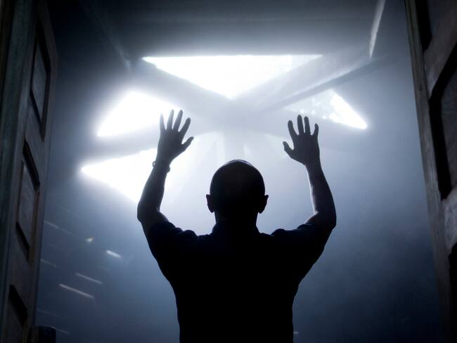 Silueta de un hombre con las manos levantadas contra la luz que viene desde arriba. Cortesía: Getty Images