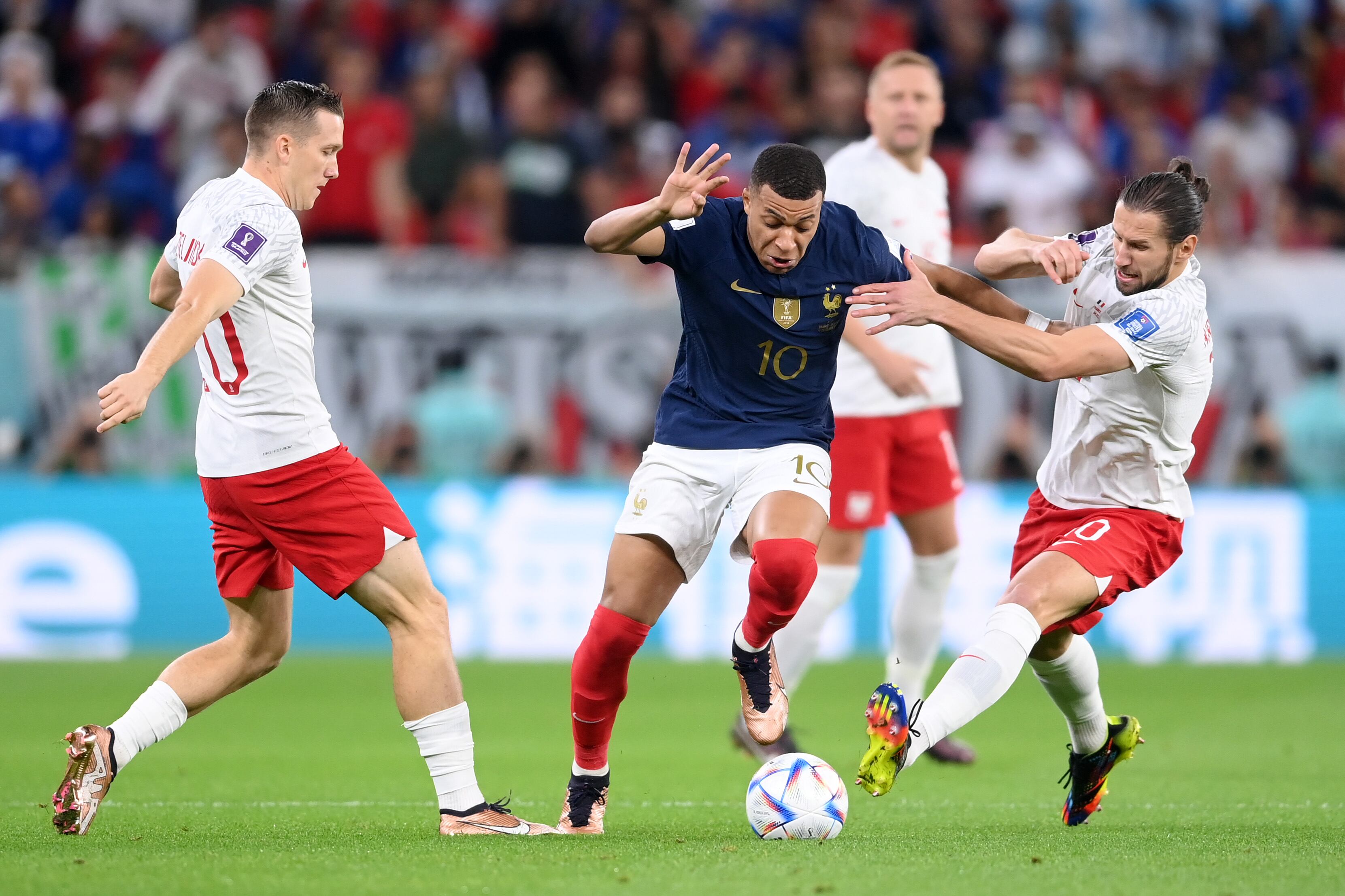 DOHA, QATAR - DECEMBER 04: Kylian Mbappe of France battles for possession with Piotr Zielinski (L) and Grzegorz Krychowiak of Poland during the FIFA World Cup Qatar 2022 Round of 16 match between France and Poland at Al Thumama Stadium on December 04, 2022 in Doha, Qatar. (Photo by Laurence Griffiths/Getty Images)