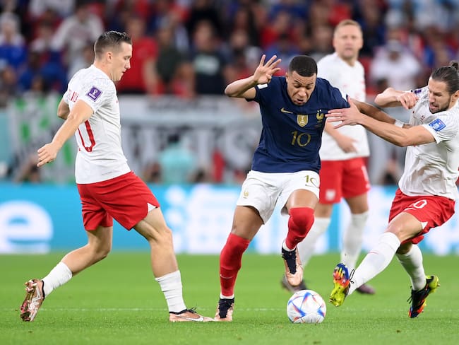 DOHA, QATAR - DECEMBER 04: Kylian Mbappe of France battles for possession with Piotr Zielinski (L) and Grzegorz Krychowiak of Poland during the FIFA World Cup Qatar 2022 Round of 16 match between France and Poland at Al Thumama Stadium on December 04, 2022 in Doha, Qatar. (Photo by Laurence Griffiths/Getty Images)