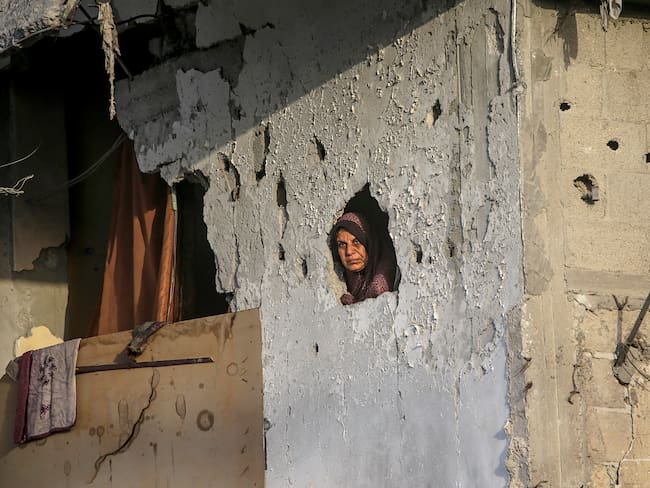 Una mujer palestina mira desde el interior de su casa destruida en la ciudad de Khan Younis, al sur de la Franja de Gaza. 
EFE/MOHAMMED SABER