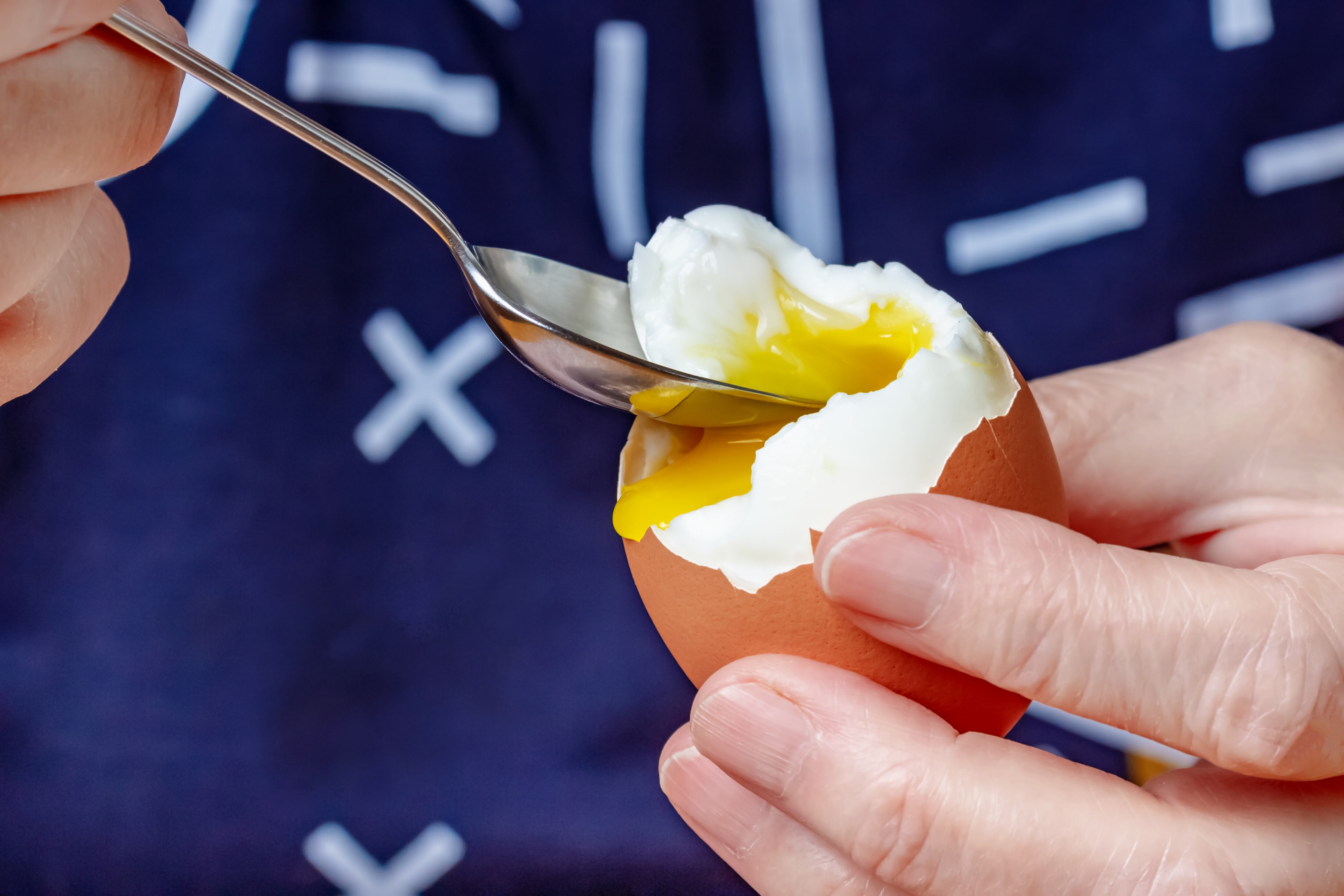 Persona comiendo huevo cocido con una cuchara (Foto vía GettyImages)
