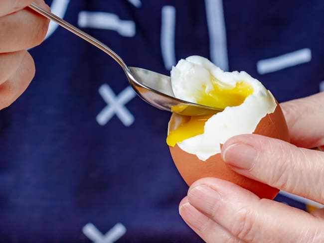 Persona comiendo huevo cocido con una cuchara (Foto vía GettyImages)