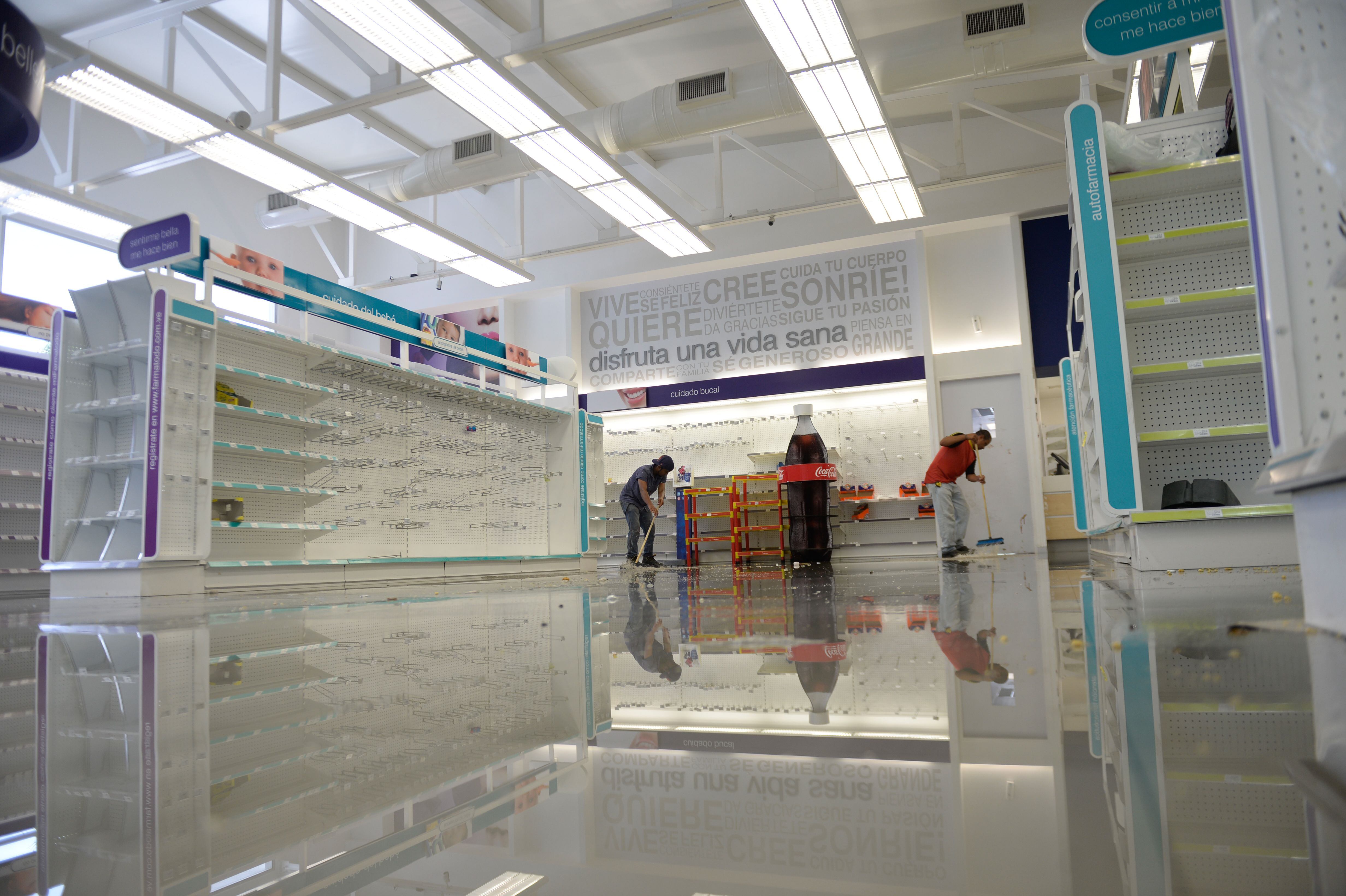 Employees clean the aisles in a looted pharmacy in Venezuela. / AFP PHOTO / FEDERICO PARRA (Photo credit should read FEDERICO PARRA/AFP via Getty Images)