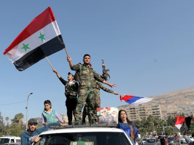 Soldados sirios ondean su bandera nacional junto con las de Irán y Rusia durante una concentración en apoyo al Gobierno sirio celebrada en la plaza de Umayyad en Damasco.