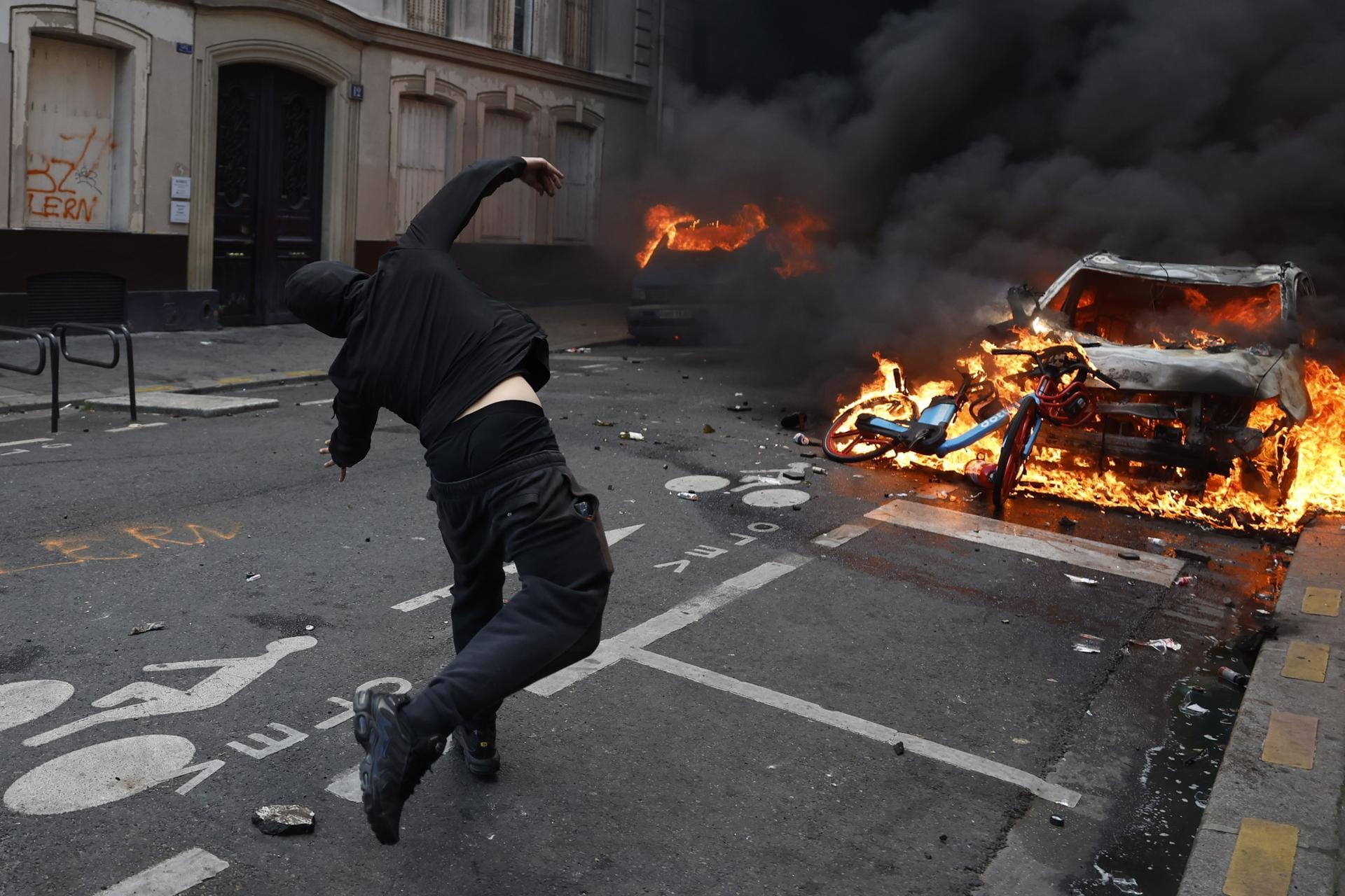 Paris (Francia), 17/10/2026.-Un manifestante lanza objetos contra un vehículo en llamas durante una protesta contra el aumento del costo de vida y los recortes en los servicios públicos en París, Francia, el 17 de octubre de 2026.  (Protestas, Francia) EFE/EPA/MOHAMMED BADRA