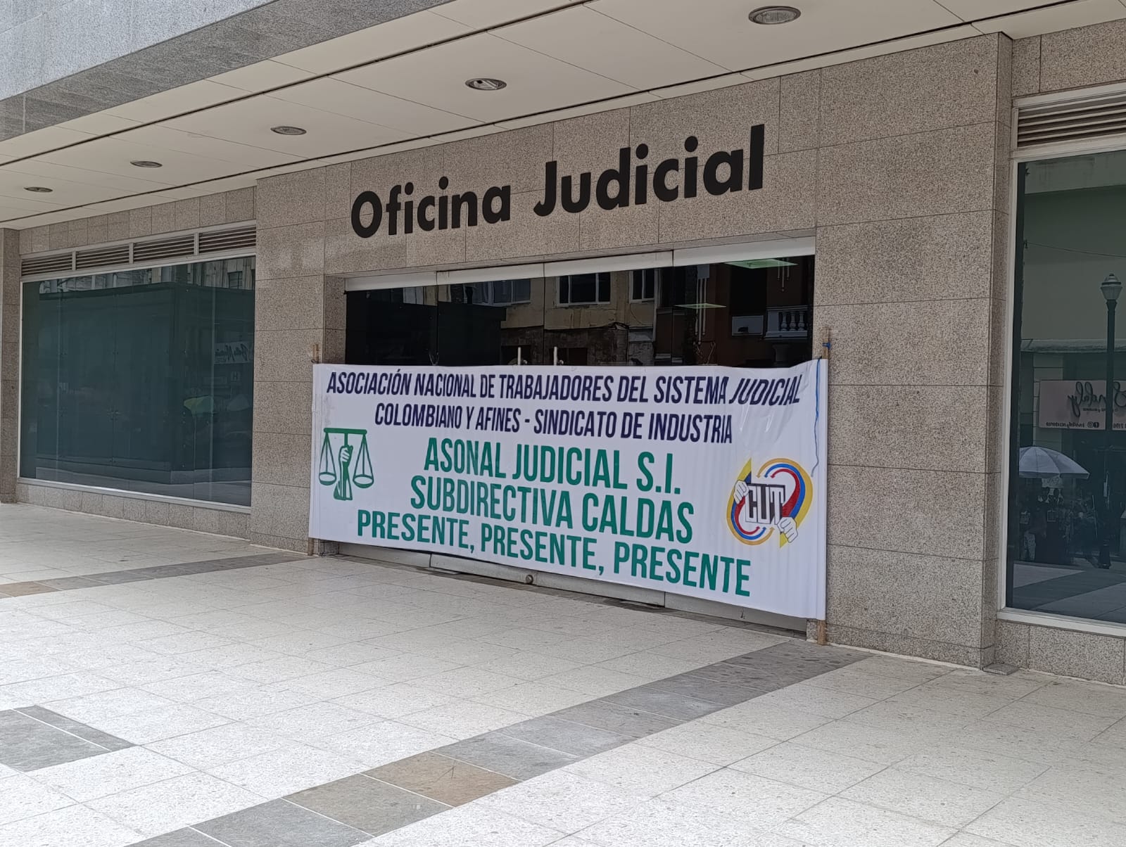 Los funcionarios están ubicados con pancartas afuera de la instalaciones de la fiscalía y el Palacio de justicia en Manizales.