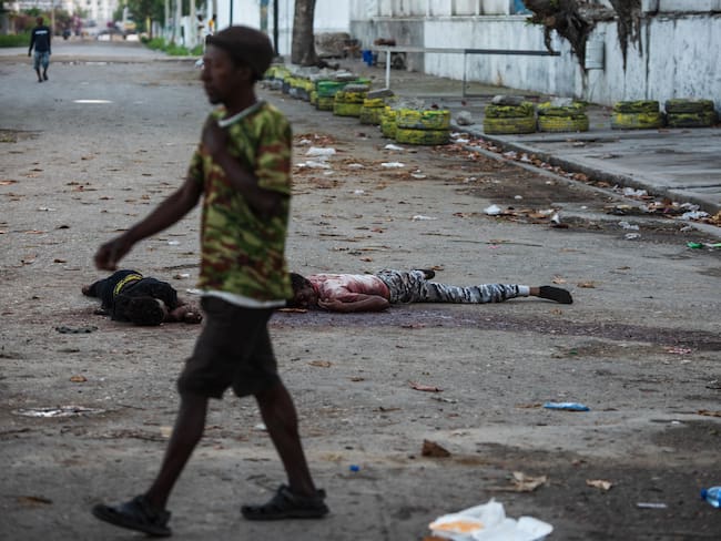 AME4903. PUERTO PRÍNCIPE (HAITÍ), 03/03/2024.- Un hombre pasa frente uno cadáveres este domingo, en una calle de Puerto Príncipe (Haití). Al menos una decena de personas murió tras el ataque anoche a la prisión civil de Puerto Príncipe por parte de bandas armadas, que habrían liberado a numerosos delincuentes importantes durante su asalto al presidio. EFE/ Johnson Sabin ATENCIÓN EDITORES: CONTENIDO GRÁFICO EXPLÍCITO