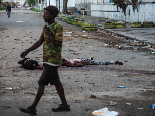 Un hombre pasa frente uno cadáveres este domingo, en una calle de Puerto Príncipe (Haití). Al menos una decena de personas murió tras el ataque anoche a la prisión civil de Puerto Príncipe por parte de bandas armadas, que habrían liberado a numerosos delincuentes importantes durante su asalto al presidio.
Foto: EFE/ Johnson Sabin
