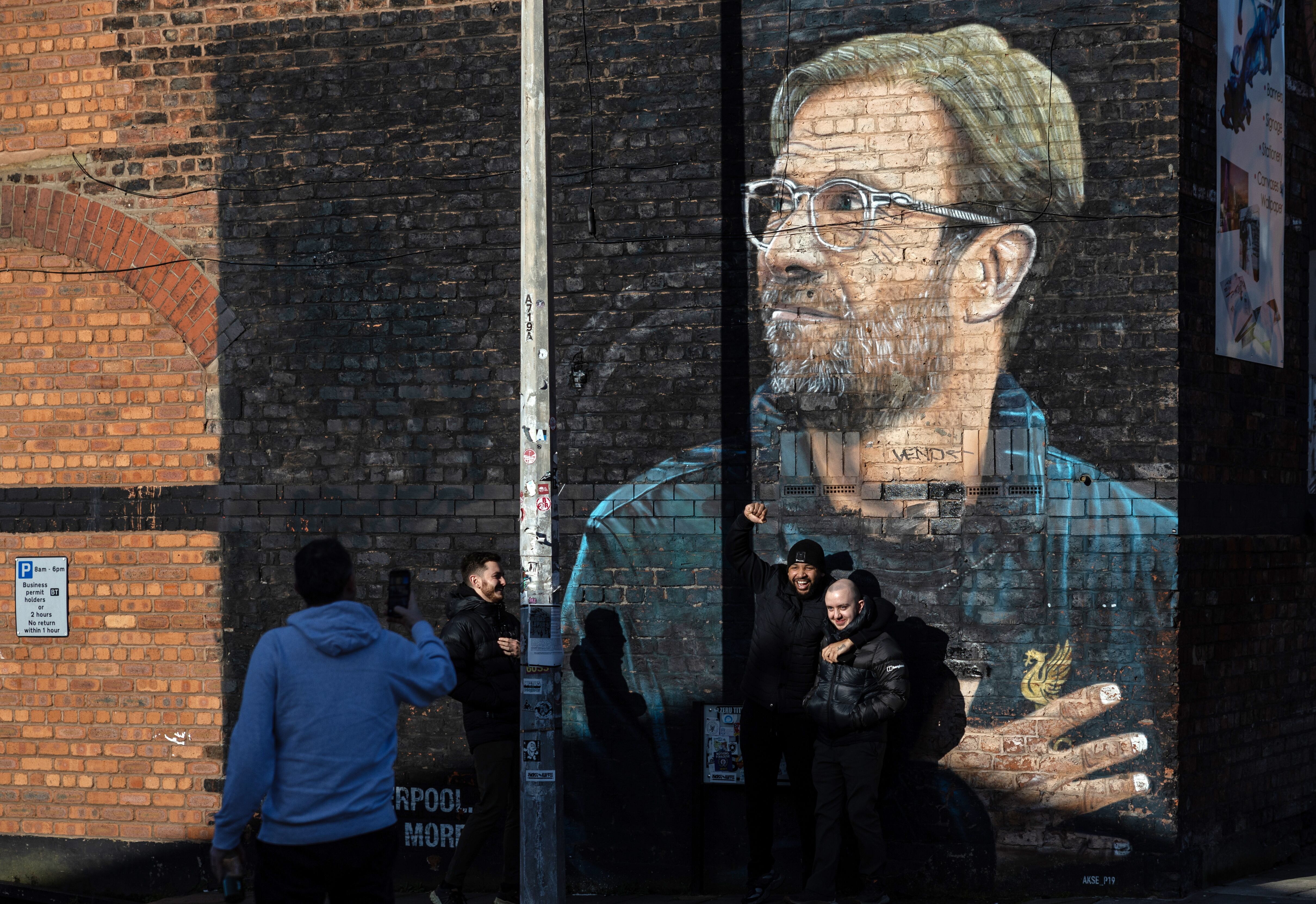 Liverpool (Reino Unido), 26/01/2024.- La gente posa para fotografías junto a un mural del entrenador de Liverpool, Jurgen Klopp, en Liverpool, este viernes. El técnico alemán anunció este viernes su decisión de abandonar el Liverpool a final de temporada, tras nueve años en los que ha ganado todos los títulos importantes, incluyendo la Liga de Campeones y la Premier League, la primera en tres décadas para los 'Reds'.- EFE/ADAM VAUGHAN