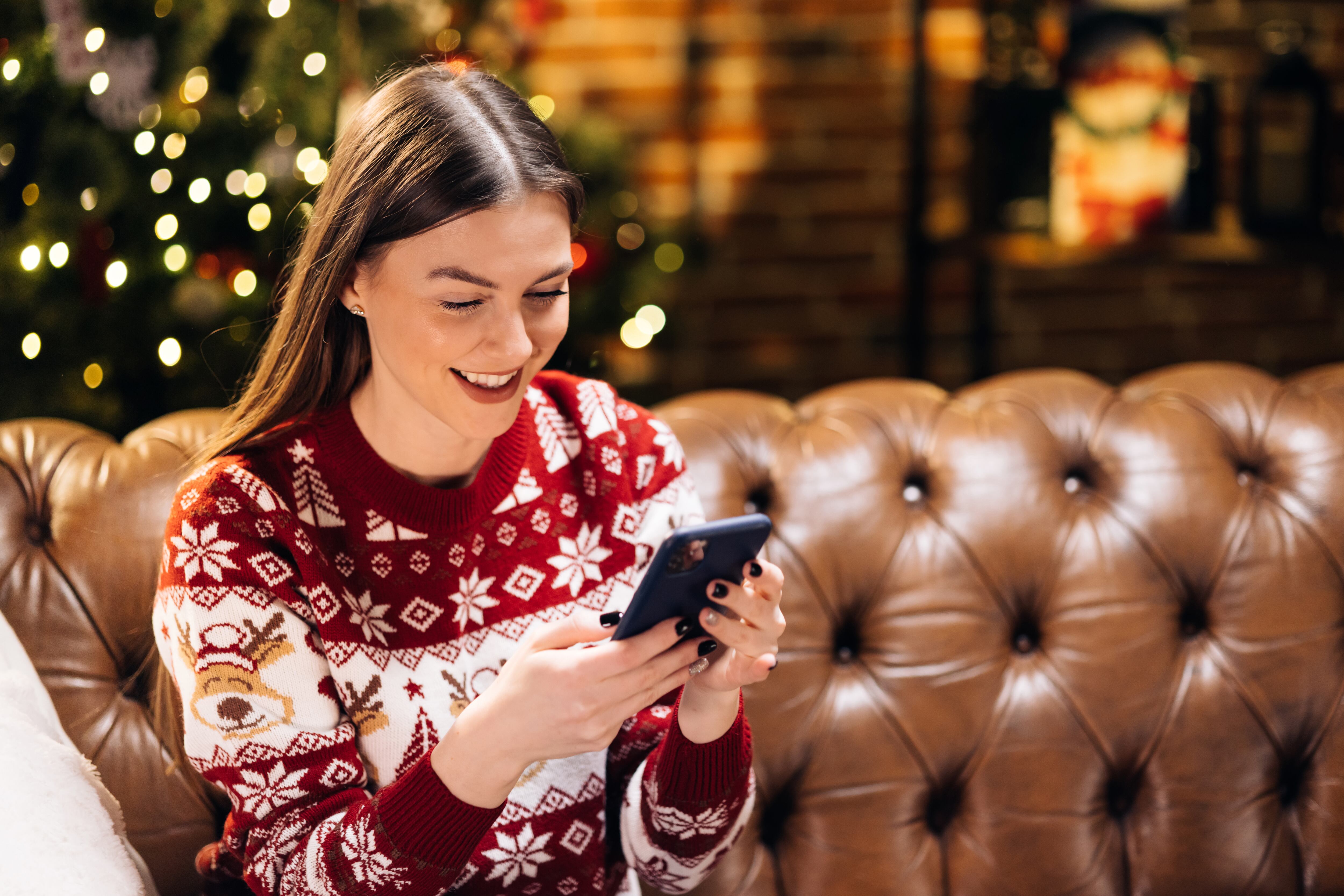 Mujer durante la Navidad chateando por su celular. (Foto vía Getty Images)