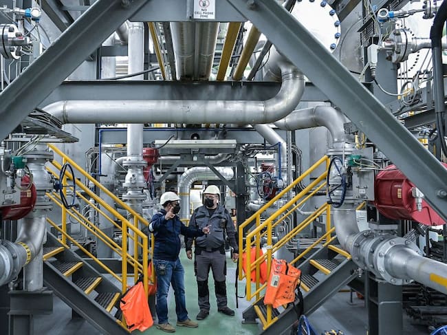 Kivuwatt Director Priysham Nundah (L) and David Krasner gas production manager are seen inside the barge extracting methane gas on Lake Kivu, at the Kivuwatt power plant in Kibuye, Karongi District, in the Western Province of Rwanda, on November 1, 2021. - Thousands of years of volcanic activity has caused a massive accumulation of methane and carbon dioxide to dissolve in the depths of lake Kivu, enough to prove monumentally destructive if released.If triggered, a so-called limnic eruption would cause "a huge explosion of gas from deep waters to the surface" resulting in tsunamis and a poisonous gas cloud that would put the lives of millions at risk.
Only three such killer lakes exist in the world: Kivu, and Lakes Nyos and Monoun in northwest Cameroon.
KivuWatt, the only project of its kind anywhere in the world, saw an opportunity to tap these abundant gases for energy generation.
the facility pumps water saturated with carbon dioxide and methane from around 350 metres (1,150 feet) to the surface.
As it rises, the water and gas separate as the pressure changes.
The extracted methane is sent through a pipeline to a second facility located onshore in Rwanda, where the biogas is transformed into electricity.
The carbon dioxide is pumped back into the lake at a precise enough depth to ensure the delicate balance is not upset.
As the methane is gradually removed, pressure is reduced in the lake, in turn lowering the risk of a limnic eruption. (Photo by Simon MAINA / AFP) (Photo by SIMON MAINA/AFP via Getty Images)