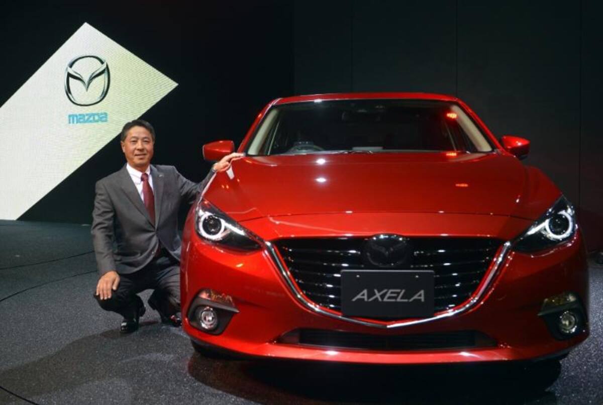 El presidente de la marca de automóviles Mazda Motor Corp. , Masamichi Kogai, posa junto al nuevo modelo Axela en el 43º Salón del Automóvil de Tokio (Japón)