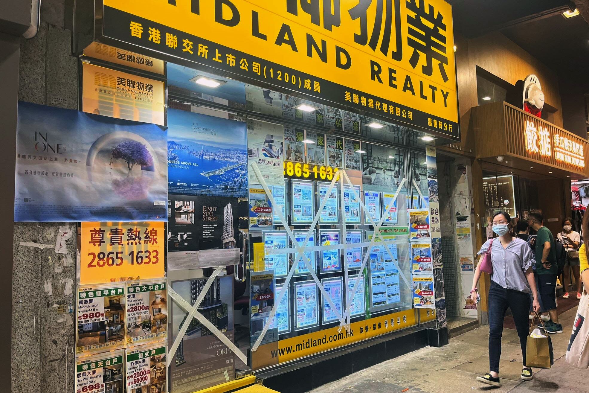 HONG KONG, 31/08/2023.- Una mujer pasea a su perro por ante una inmobiliaria de Hong Kong. El gobierno de Hong Kong ordenó hoy a la administración que se prepare para "el peor escenario posible" ante la aproximación del supertifón Saola, y anunció la suspensión de su mercado de valores y el cierre de escuelas y algunos comercios a partir del viernes. EFE/ Mar Sánchez-cascado