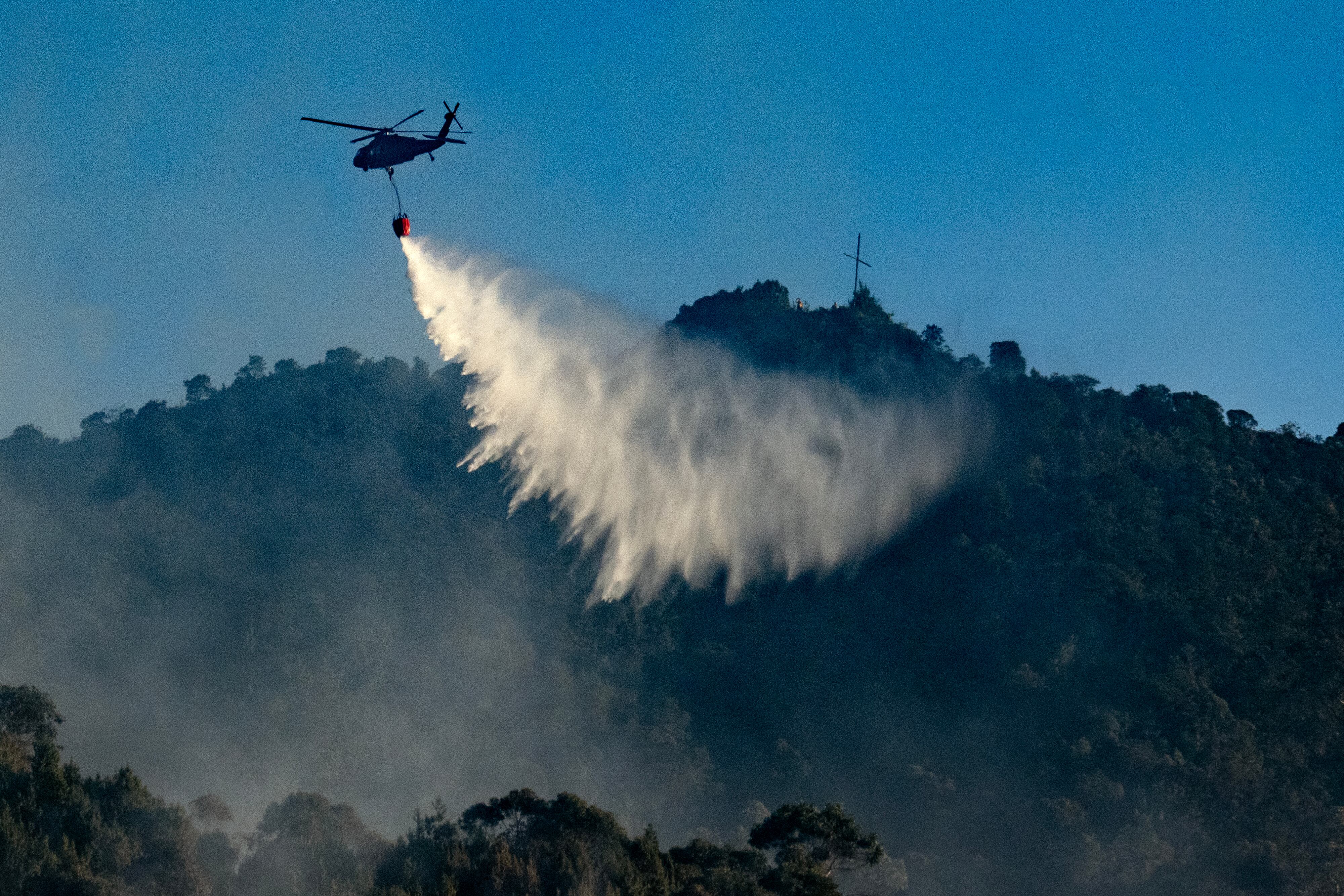 Un helicóptero de las Fuerzas Armadas arroja agua para apagar un incendio forestal. Foto: Archivo.